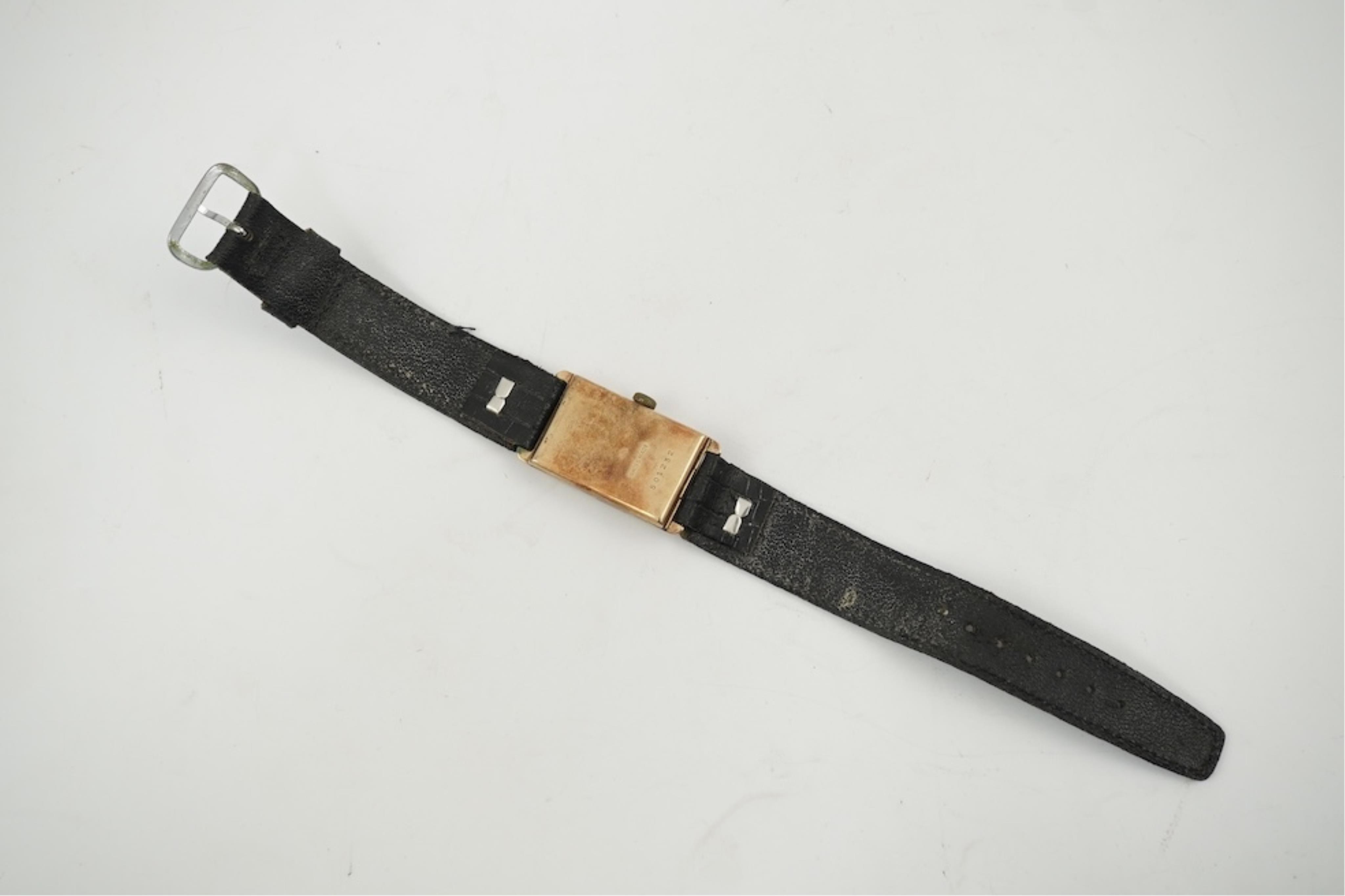 An early 1930's 9ct gold Swiss 'Jump Hour' rectangular cased manual wind wrist watch, case diameter 20mm, on a leather strap, gross weight 23 grams.